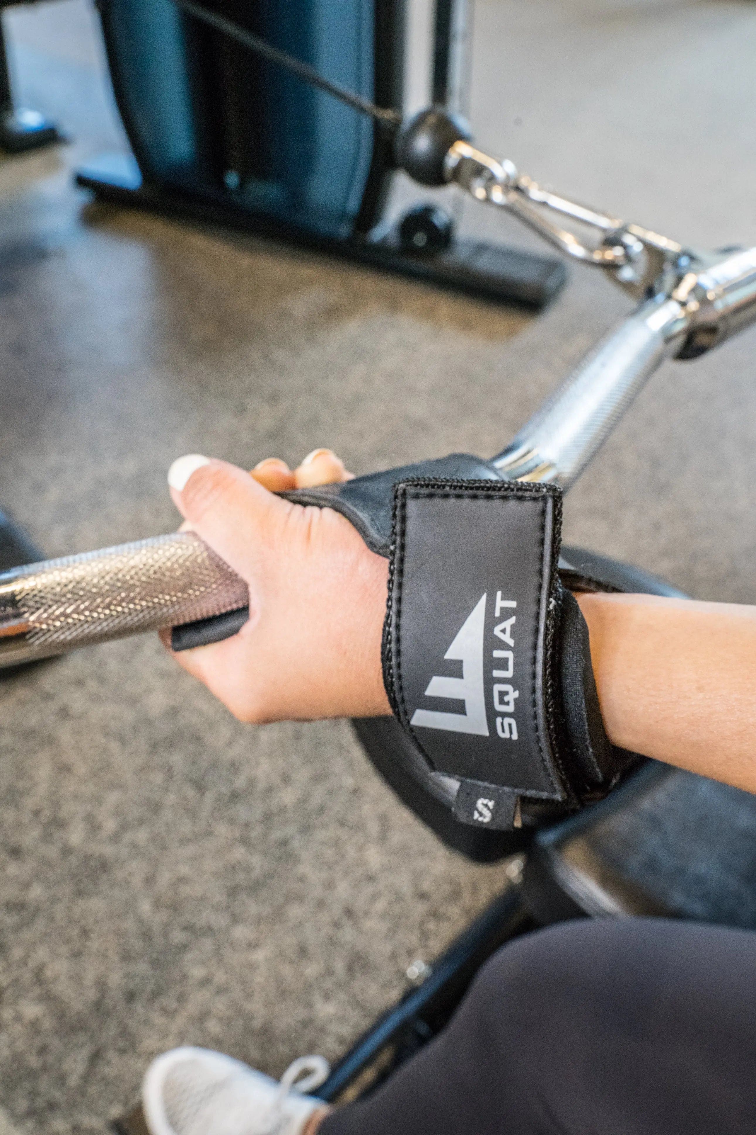 Female holding a bar with weight lifting straps