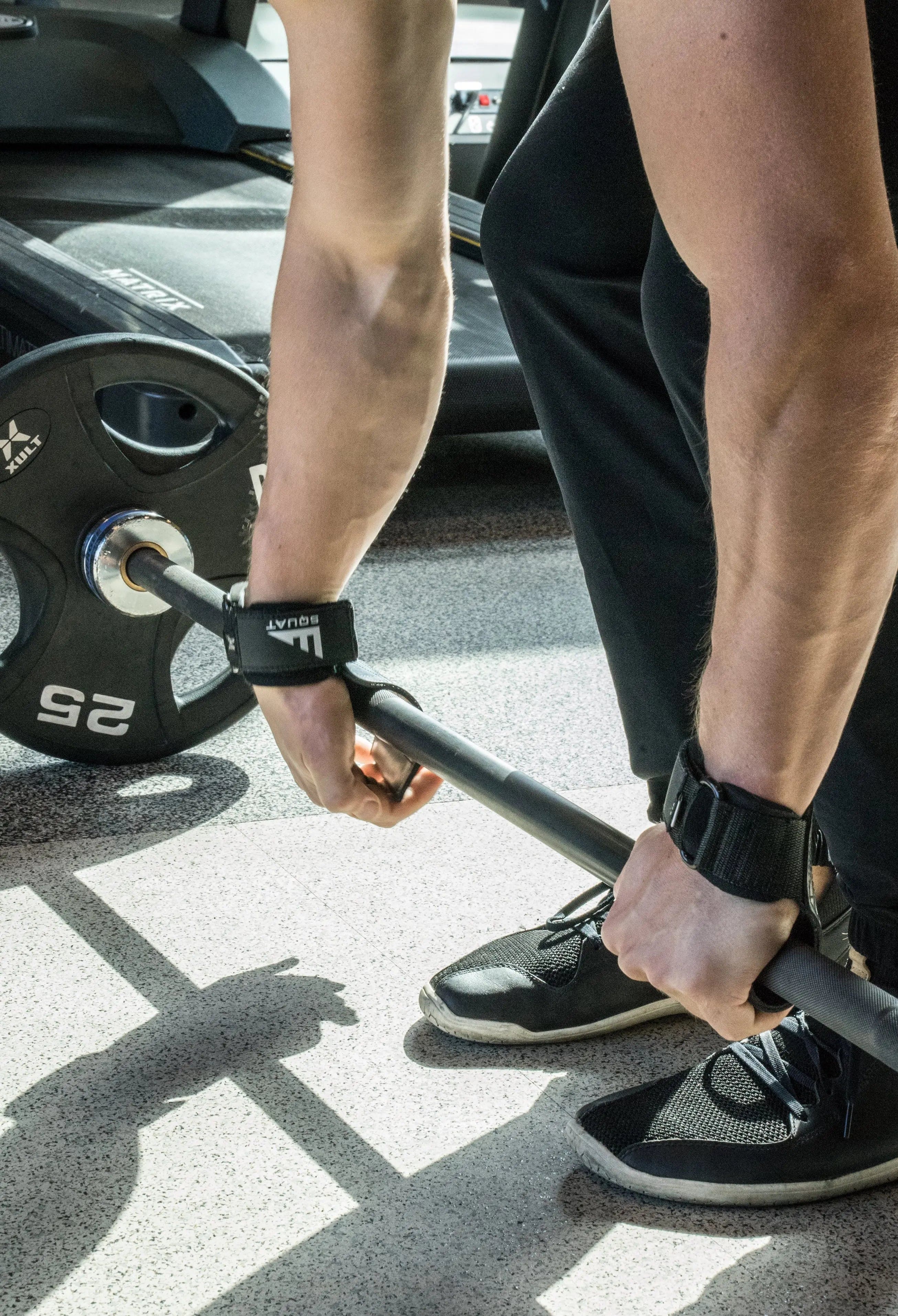 Person wrapping weightlifting straps around a barbell